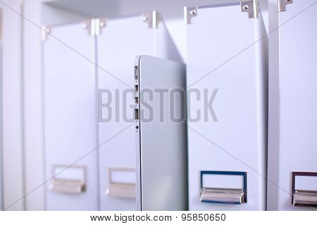 File folders, standing on  shelves in the background