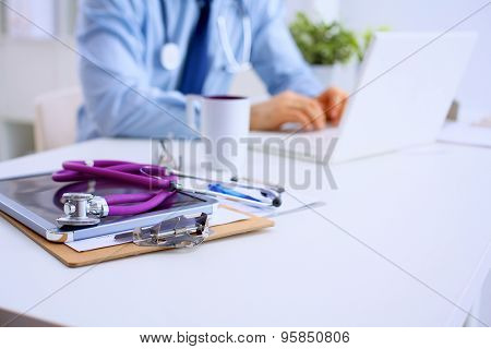 Male doctor using a laptop, sitting at his desk