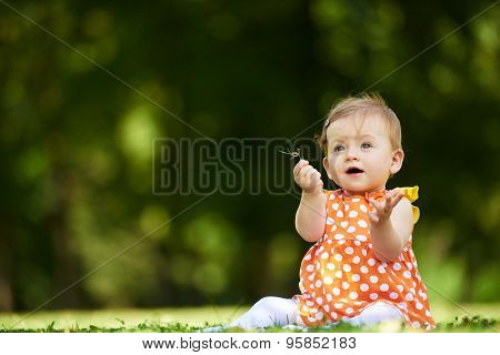 happy young baby child sittng on grass on beautiful summer day in park