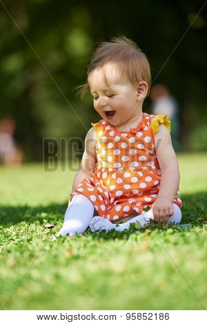 happy young baby child sittng on grass on beautiful summer day in park