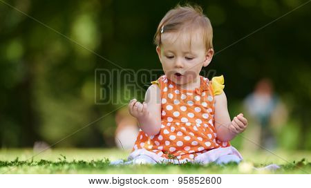 happy young baby child sittng on grass on beautiful summer day in park