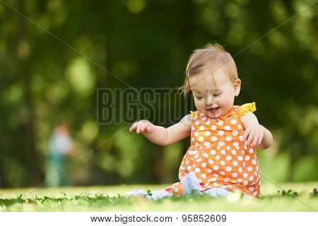 happy young baby child sittng on grass on beautiful summer day in park