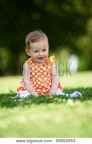 happy young baby child sittng on grass on beautiful summer day in park