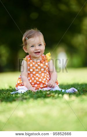 happy young baby child sittng on grass on beautiful summer day in park