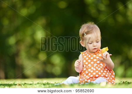happy young baby child sittng on grass on beautiful summer day in park