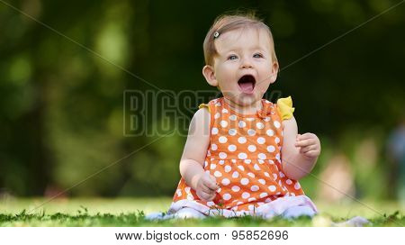 happy young baby child sittng on grass on beautiful summer day in park