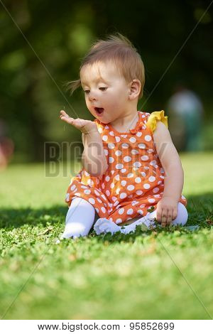 happy young baby child sittng on grass on beautiful summer day in park