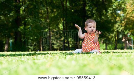 happy young baby child sittng on grass on beautiful summer day in park