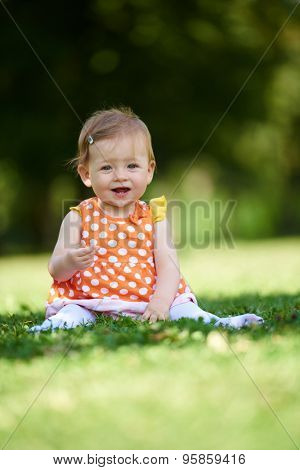 happy young baby child sittng on grass on beautiful summer day in park