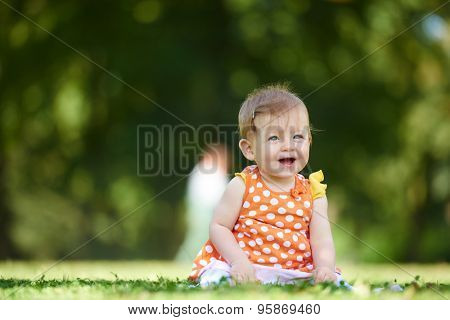 happy young baby child sittng on grass on beautiful summer day in park