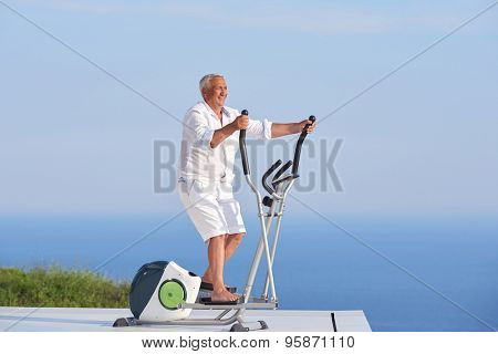 healthy senior man working out on gym treadmill machine at modern home terace with ocean view
