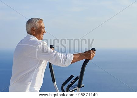 healthy senior man working out on gym treadmill machine at modern home terace with ocean view