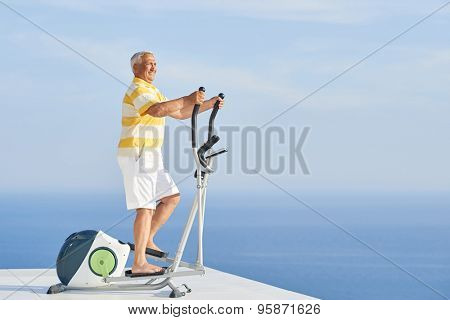 healthy senior man working out on gym treadmill machine at modern home terace with ocean view