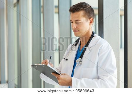 smart medical intern doctor writing on clipboard in office