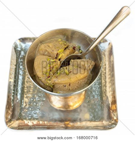 A photo of kulfi, traditional Indian ice cream, in a typical bowl, on white background. Selective focus on the dessert