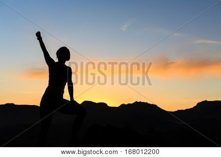 Girl hiking silhouette in mountains sunset and ocean. Female hiker climber or trail runner with arms outstretched on mountain top looking at beautiful night sunset inspirational landscape.