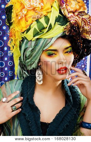 beauty bright woman with creative bright make up, many shawls on head like cubian, ethno look closeup