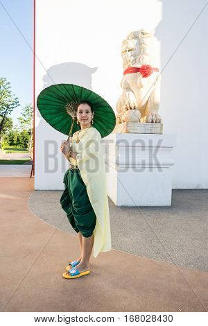 Portrait of woman dressing in Thai traditional costume using an umbella