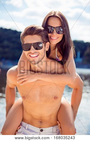 Portrait Of Handsome Man Carrying His Wife On Back. Family Having Fun And Resting