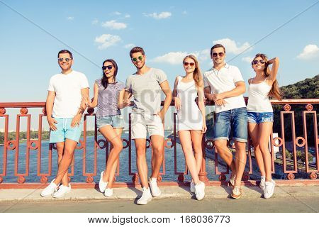 Portrait Of Happy Smiling Frinds Resting On Weekend On The Bridge