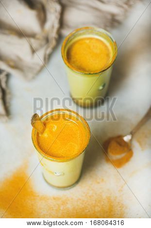 Golden milk with turmeric powder in glasses over grey marble background. Health and energy boosting, flu remedy, natural cold fighting drink. Clean eating, dieting, detox, weight loss concept