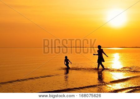 Mother and daughter playing on the beach at sunset