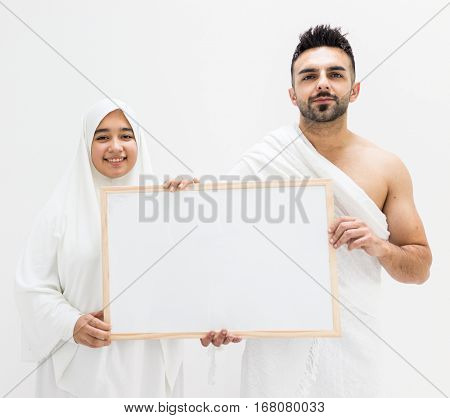 Muslim man posing as ready for Hajj visiting Kaaba in Mecca holding white board for copy space your text or image