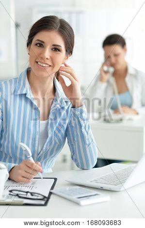 Portrait of a young female office worker, using laptop