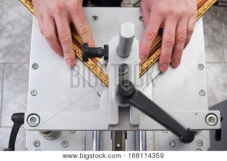 Craftsman working on frame in frameshop. Professional framer hand holding frame angle. Top view.