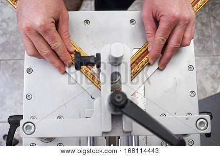 Craftsman working on frame in frameshop. Professional framer hand holding frame angle. Top view.