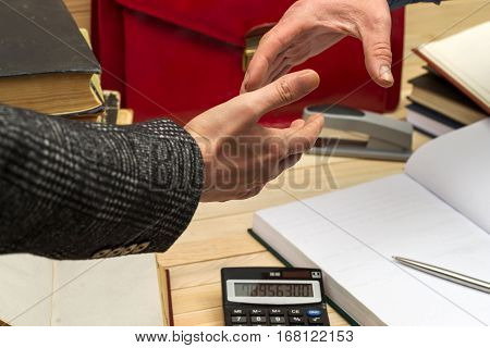 Business concept. Business partners handshaking after signing contract. Pertnership. On a wooden table books, documents, calculator, red briefcase
