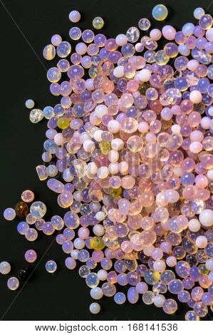 Macro of silica gel balls laying on black background.Its use to prevent mold, mildew, corrosion, odours and other moisture damage.