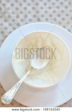 Emty ceramic bowl of white yoghurt and spoon