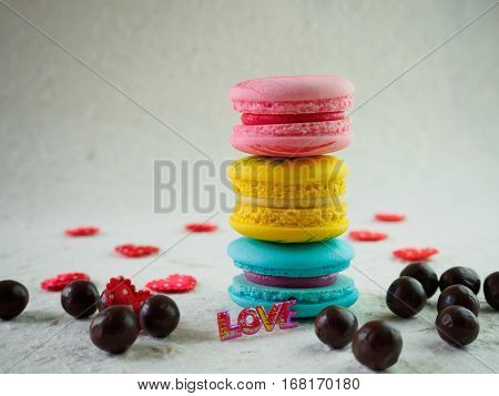 Chocolate and red hearts and tower of sweet and colorful french macaroons or macarons on rough white paper Dessert for St valentine day. .