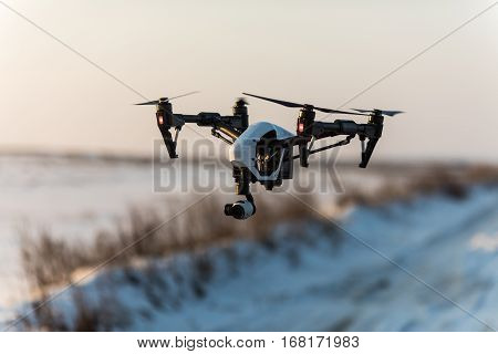 White drone with digital camera flying and landing on snow in winter