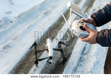 Man with remote control prepare white drone with digital camera for start flying in winter weather with snow