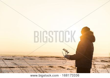 Man with remote control of drone against sky