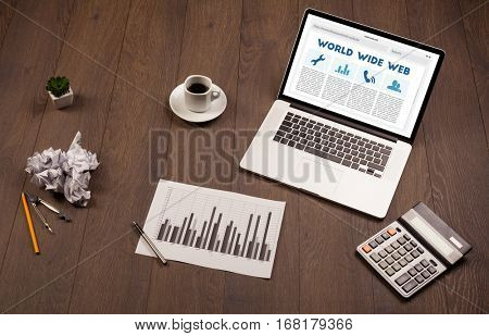 Laptop computer on wooden desk with office suplies
