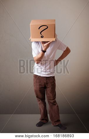 Young man standing and gesturing with a cardboard box on his head with question mark