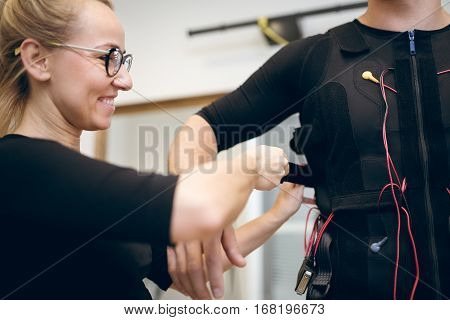 Happy Woman Helping Man With Putting Ems Suit On