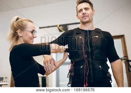 Smiling Woman Putting Ems Suit On Young Man