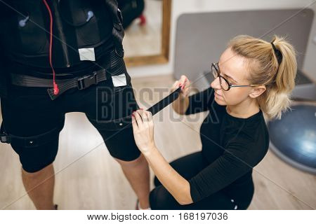 Woman Fastening Belt On Man Leg