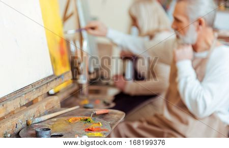 Hobby and job. Delighted talented concentrated artist drawing a picture while spending time in painting class and working.