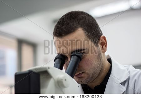 Female Medical Or Scientific Researcher Man Doctor Looking Through A Microscope In A Laboratory. You