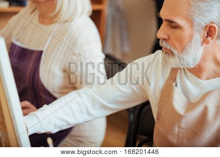 Common activity. Close up of talented elderly colleagues drawing together while sitting in painting class and enjoying their hobby