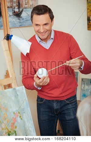 Improve yourself. Ambitious handsome young artist teaching people and spending time in painting studio while helping them to draw.
