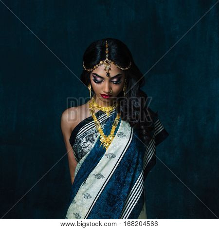 Bengali girl in a traditional costume with her eyes down in photostudio