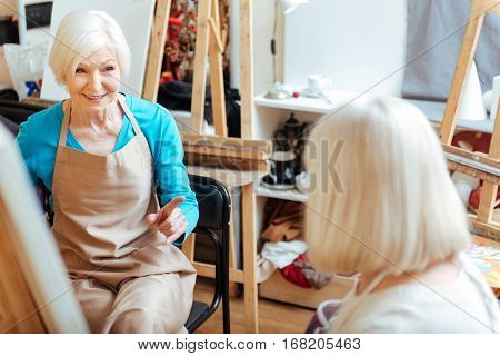 Common hobby. Elderly happy ambitious women talking and spending time in painting class while drawing.