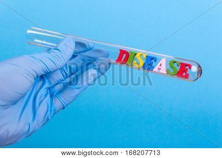 Word disease of colored wooden letters in test-tube. Hand in glove holding a test tube on a blue background