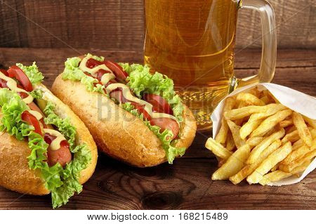 Hot Dogs With Glass Of Beer With French Fries On Wooden Board